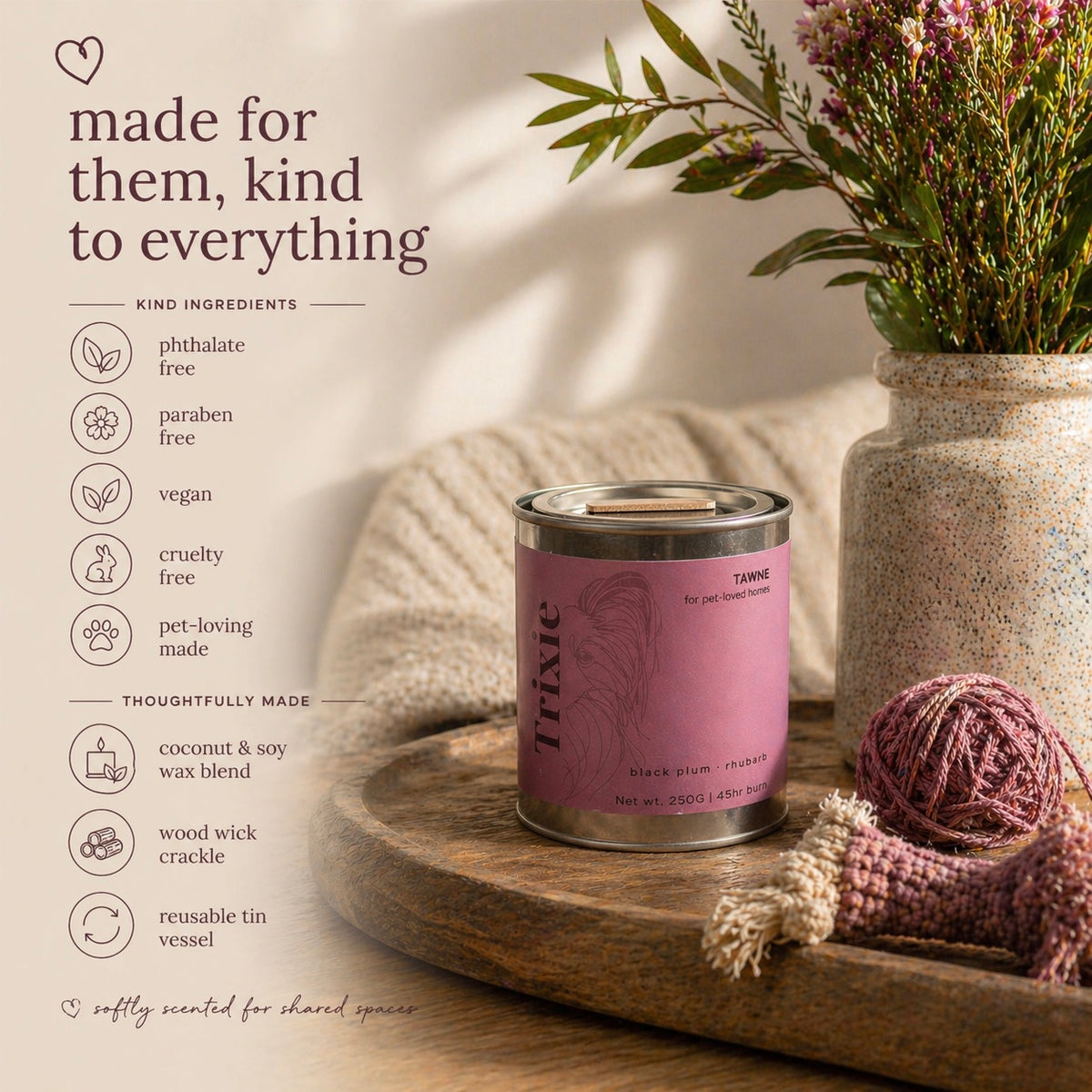 Candle with pink label on a wooden tray, surrounded by decorative elements like yarn and flowers.